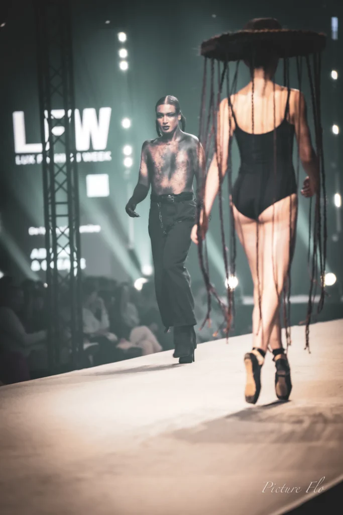 Youness entre sur le podium tandis que Léa, en pointes sous le chapeau de tresses, s’éloigne, Lux Fashion Week 2026, Arlon
