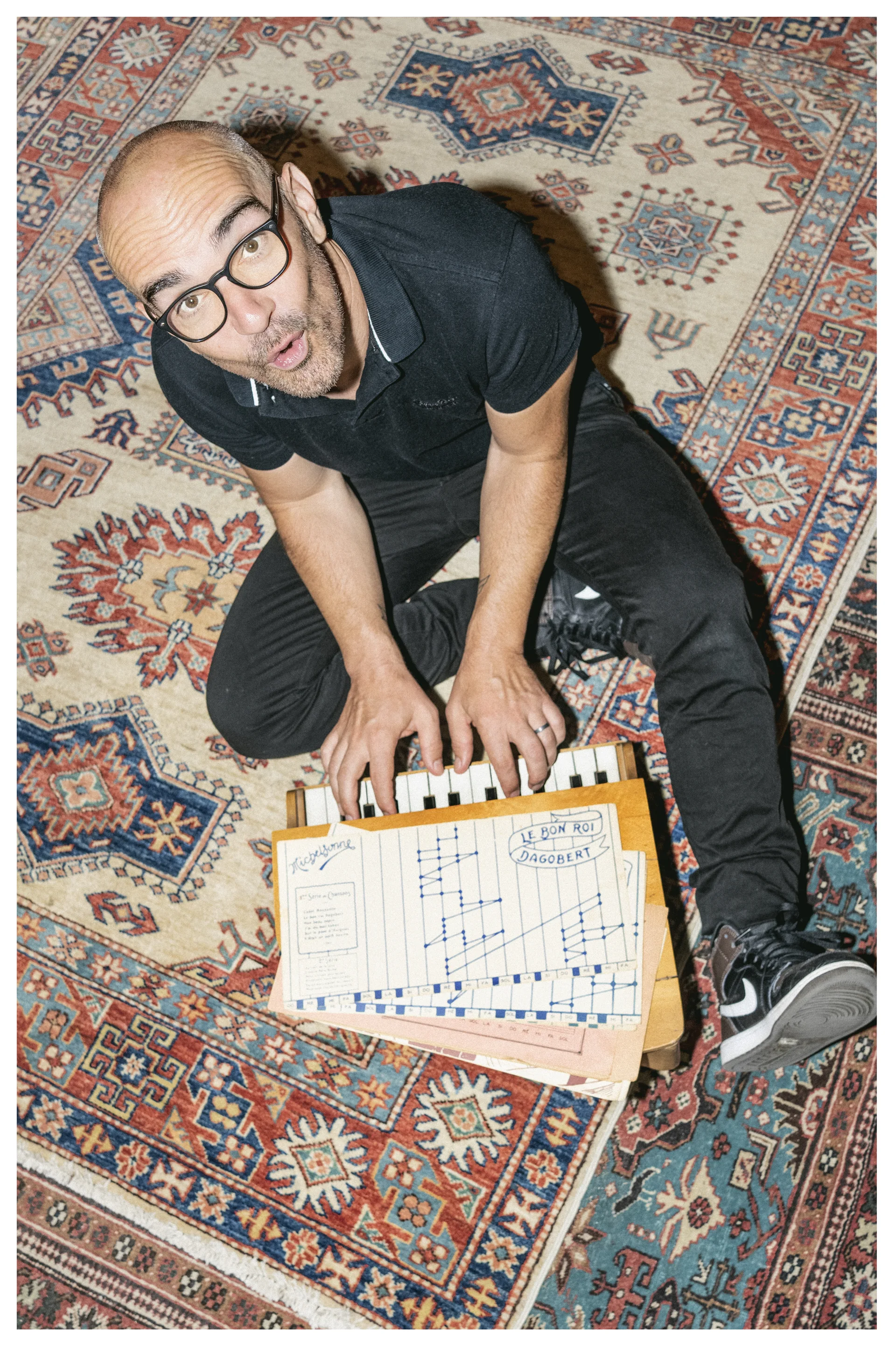 Aldebert assis sur un tapis devant un petit clavier et des partitions