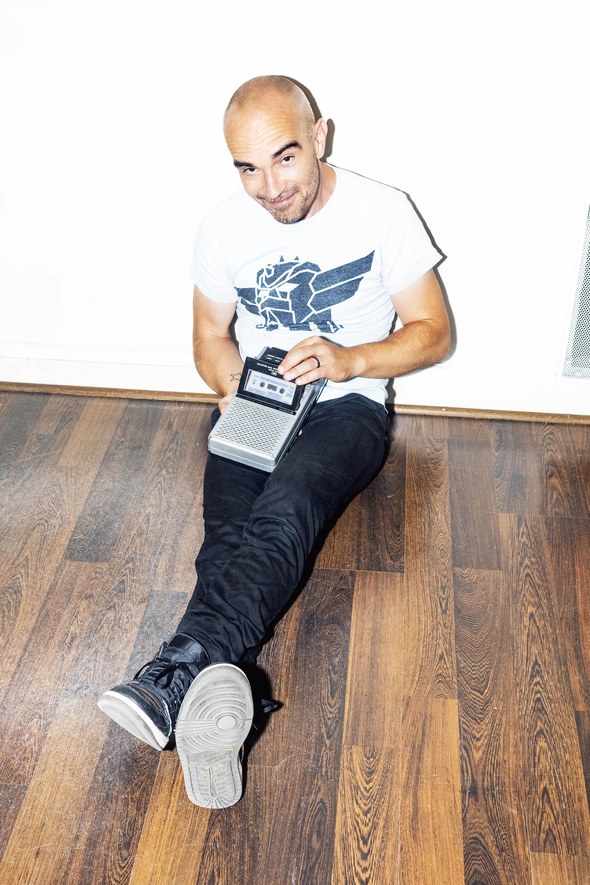 Aldebert assis sur un parquet, un vieux magnétophone en main
