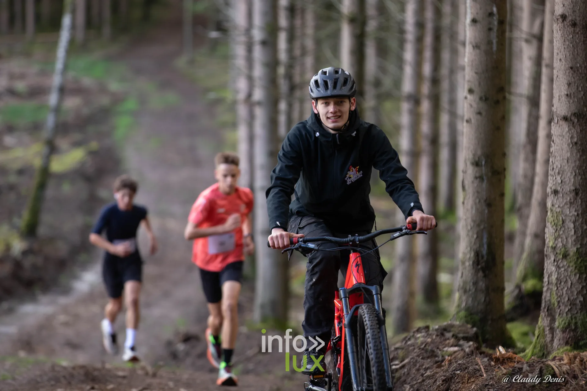 Backyard de Chôdes 2026 à Malmedy : un vététiste et deux jeunes coureurs dans la forêt d’épicéas (photo Claudy Denis)