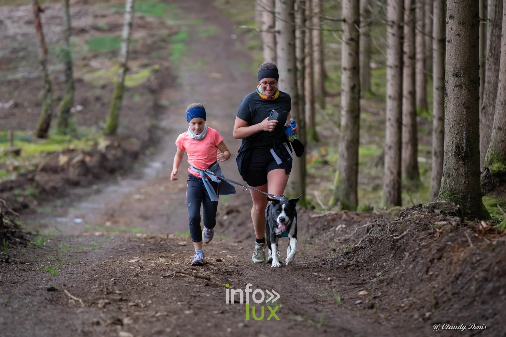 Backyard de Chôdes 2026 à Malmedy : une jeune participante, une coureuse et un chien dans la forêt d’épicéas (photo Claudy Denis)