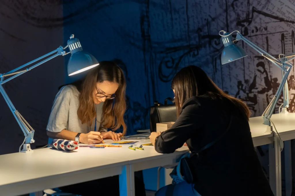 Deux visiteuses dessinent à l’atelier créatif de Van Gogh: The Immersive Experience