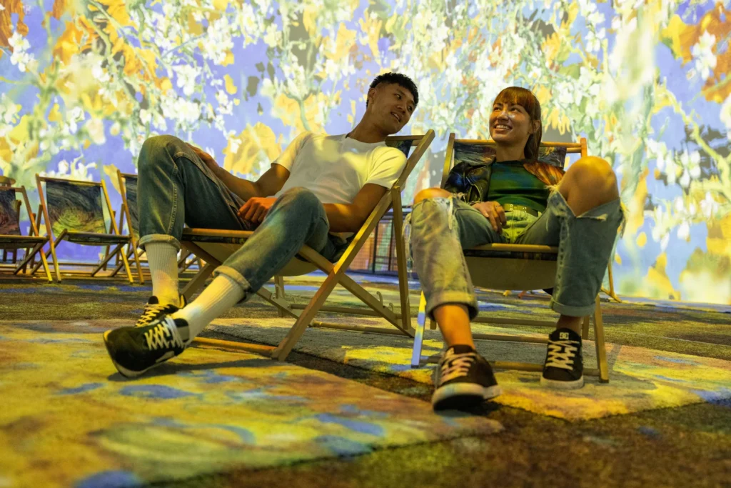 Deux visiteurs dans des transats au milieu des projections à 360° de Van Gogh: The Immersive Experience