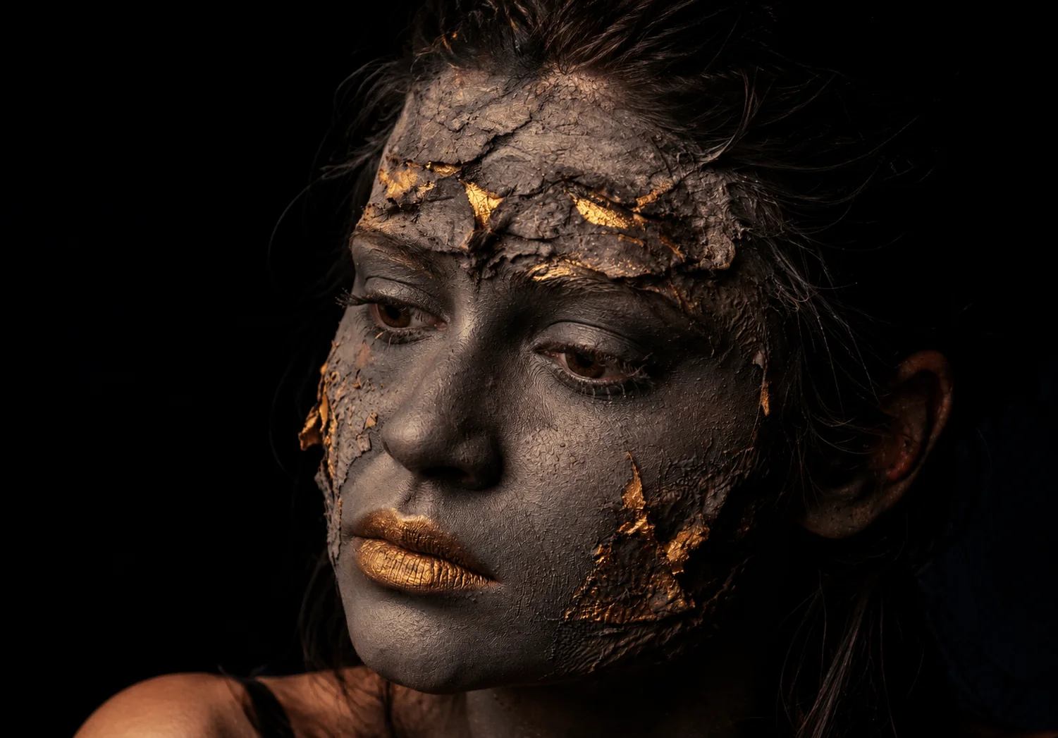 Illustration d’un visage couvert d’une croûte grise craquelée laissant apparaître de l’or