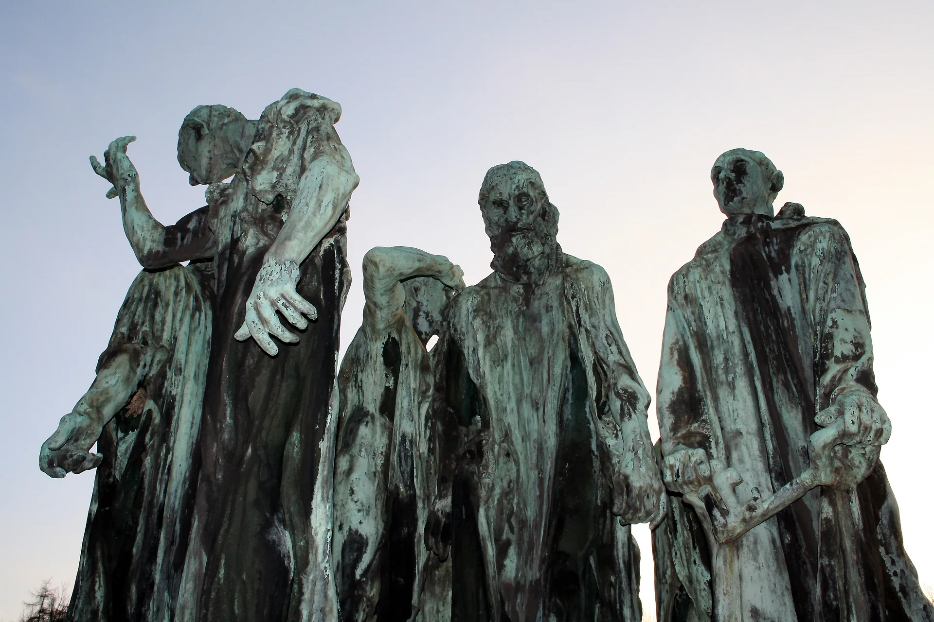 Quatre des six bourgeois du groupe en bronze de Rodin, vus en contre-plongée, à Mariemont