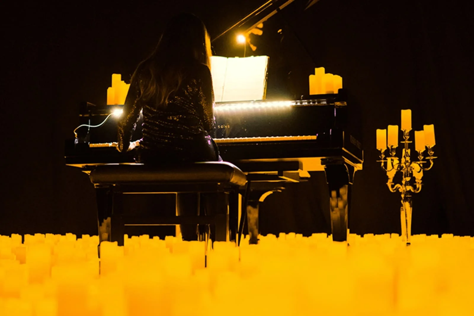 Pianiste au piano à queue entouré de bougies lors d’un concert Candlelight