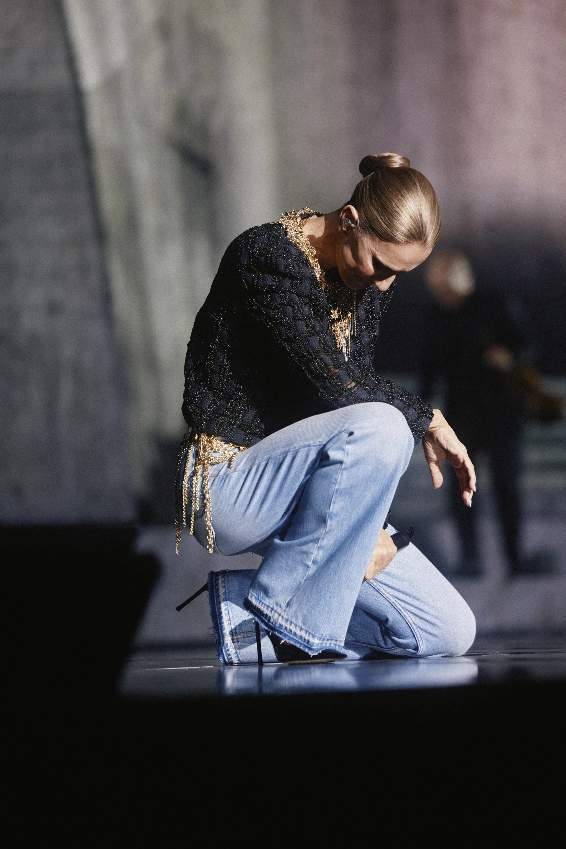 Céline Dion agenouillée sur la scène de la Plenitude Arena