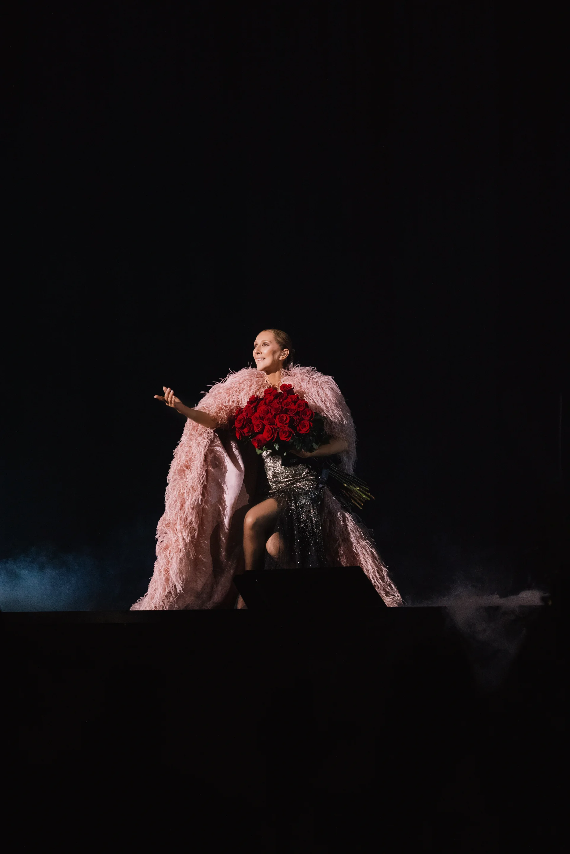 Céline Dion en manteau de plumes rose, un bouquet de roses rouges dans les bras