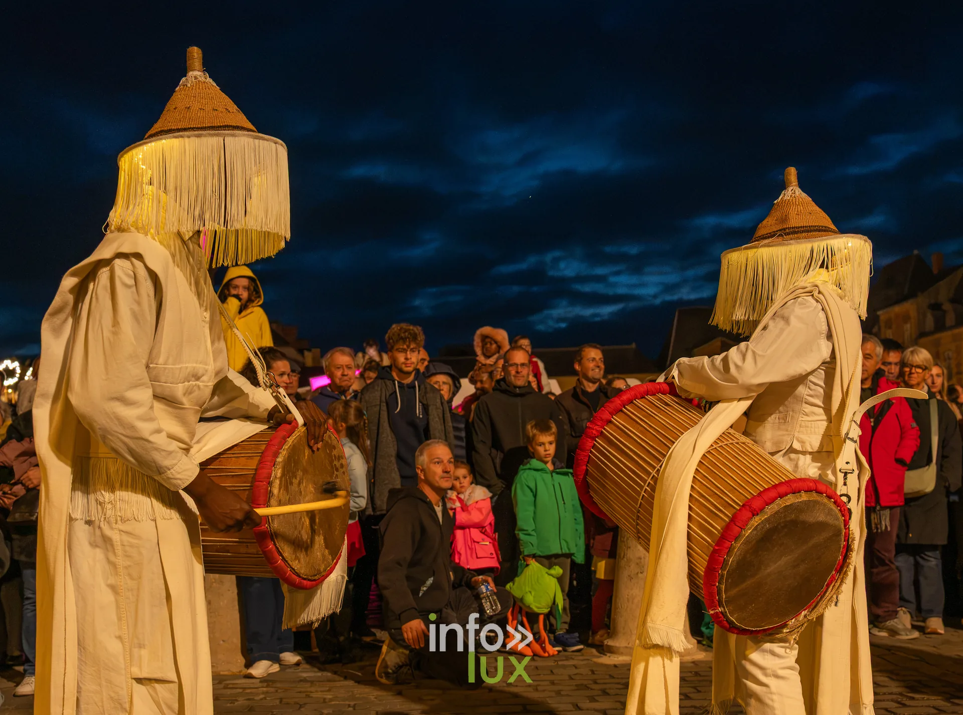 Deux percussionnistes en costume blanc à franges devant la foule, de nuit, photo Dolorès Photographie