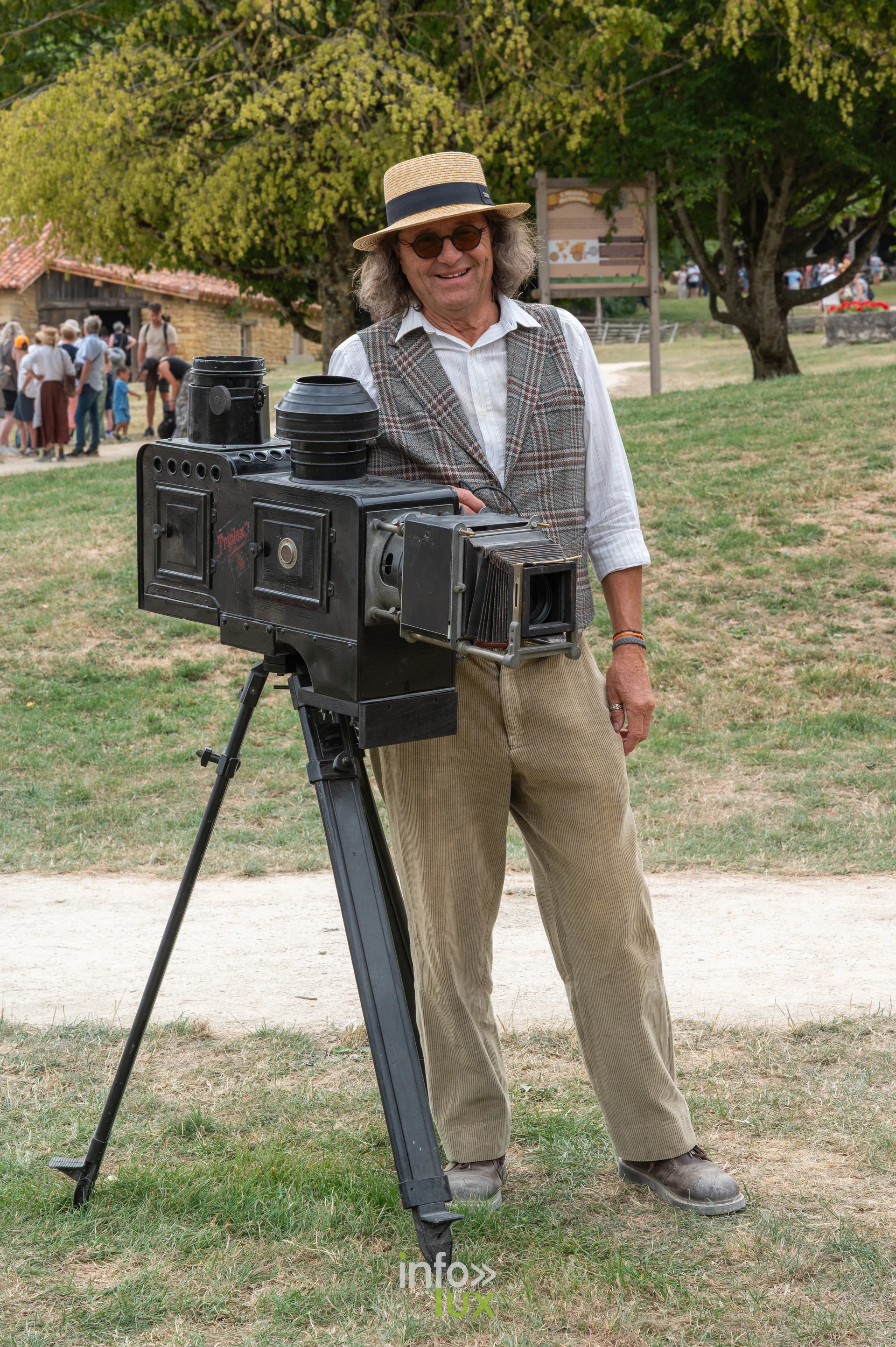 Homme posant à côté d’une ancienne caméra sur trépied, photo Dolorès Photographie