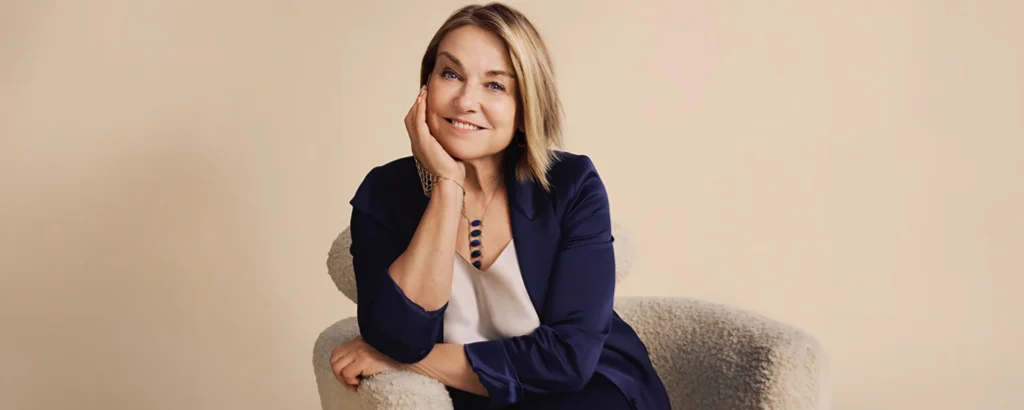 La psychothérapeute Esther Perel, souriante, assise dans un fauteuil, visuel de la tournée Strangers, Friends, and Lovers