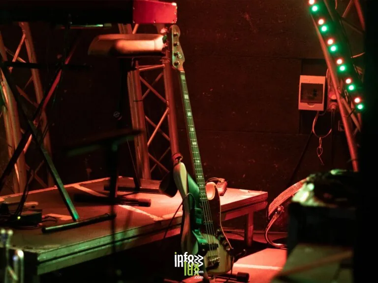 Une scène atmosphérique avec une guitare basse et des lumières à bande vibrantes, prête pour une performance en direct.