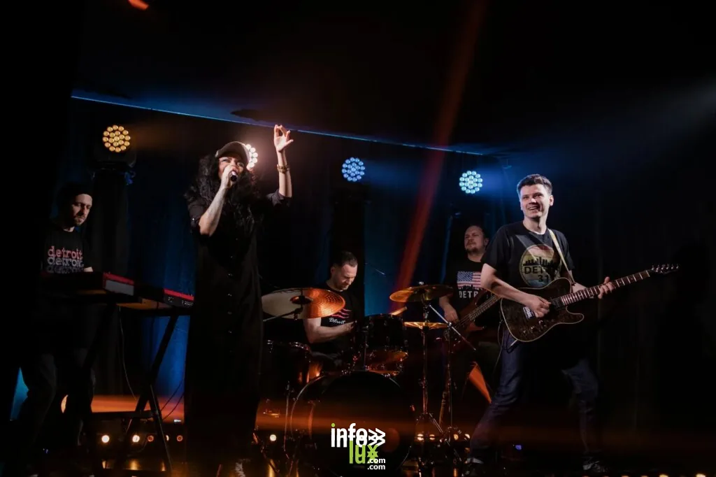 Performance musicale dynamique en direct avec un groupe de rock, un chanteur et des instruments sur scène.
