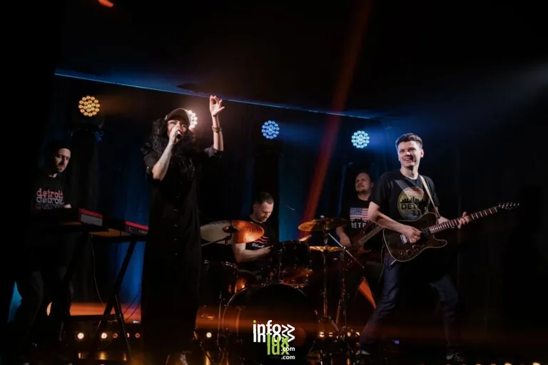 Performance musicale dynamique en direct avec un groupe de rock, un chanteur et des instruments sur scène.