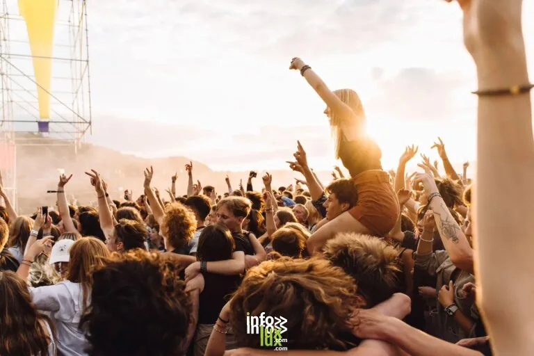 Foule énergique profitant de la musique live lors d'un festival au coucher du soleil.