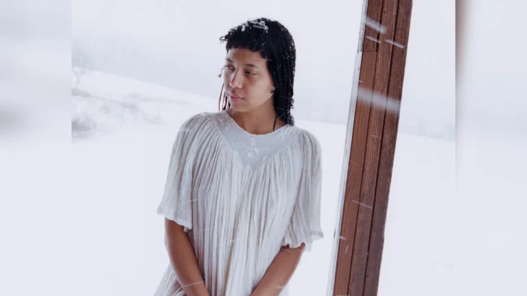 La chanteuse américaine June McDoom en robe blanche devant un paysage enneigé