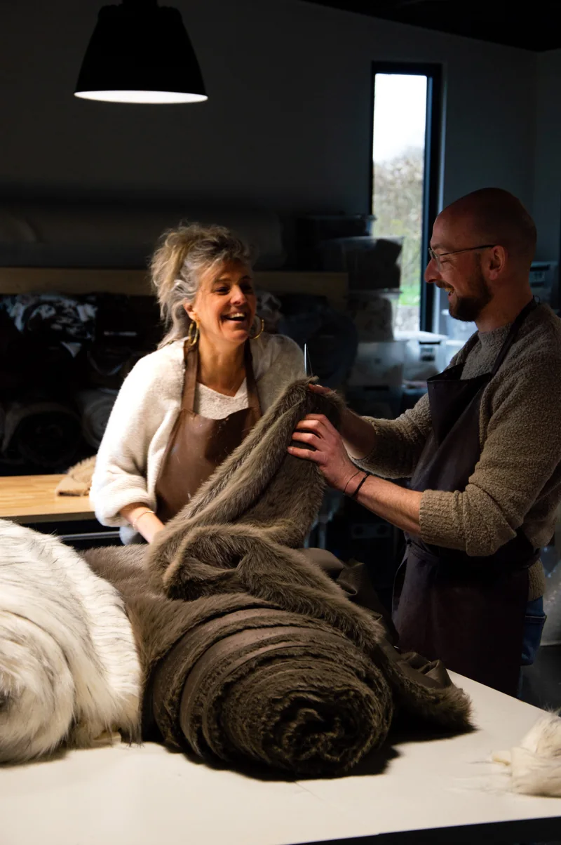 Dans l’atelier Langkâ, une femme et un homme déroulent en riant un rouleau de tissu façon fourrure brune