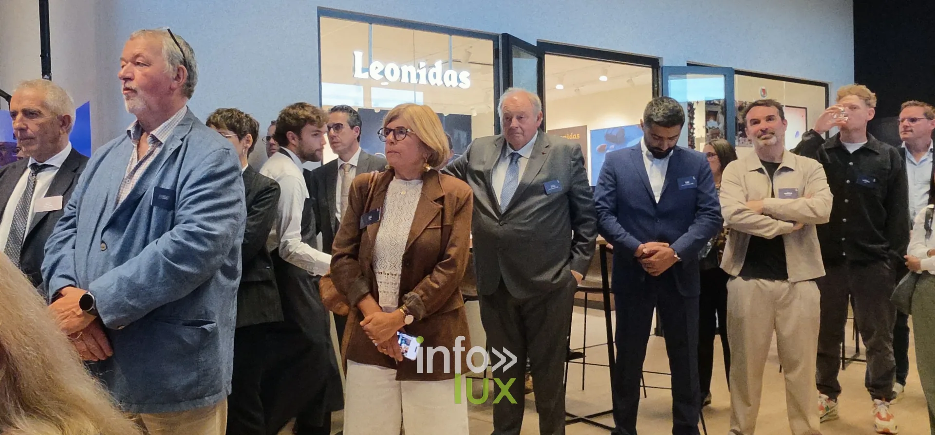 Des invités debout pendant les discours, inauguration du nouveau site Leonidas à Nivelles, 15 octobre 2026 (photo Karolyn Delisé-Hanse) — photo modifiée par ia