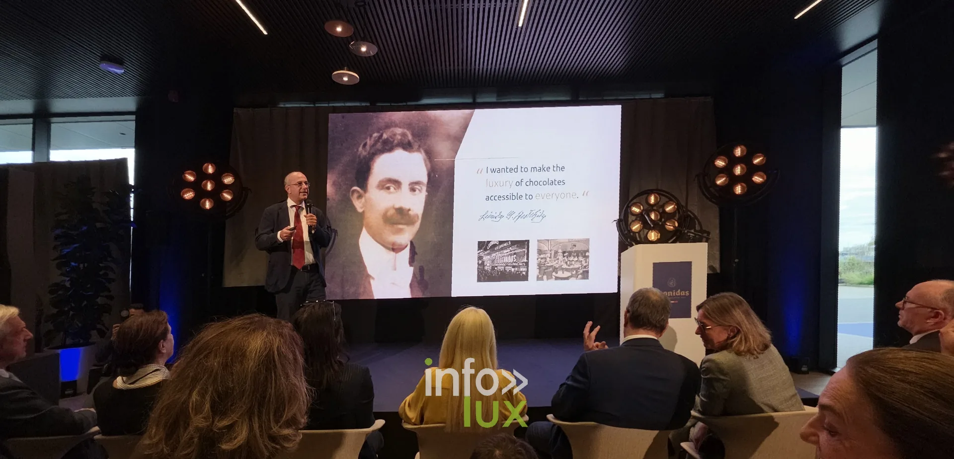 Un portrait d’archive projeté pendant les discours, inauguration du nouveau site Leonidas à Nivelles, 15 octobre 2026 (photo Karolyn Delisé-Hanse) — photo modifiée par ia