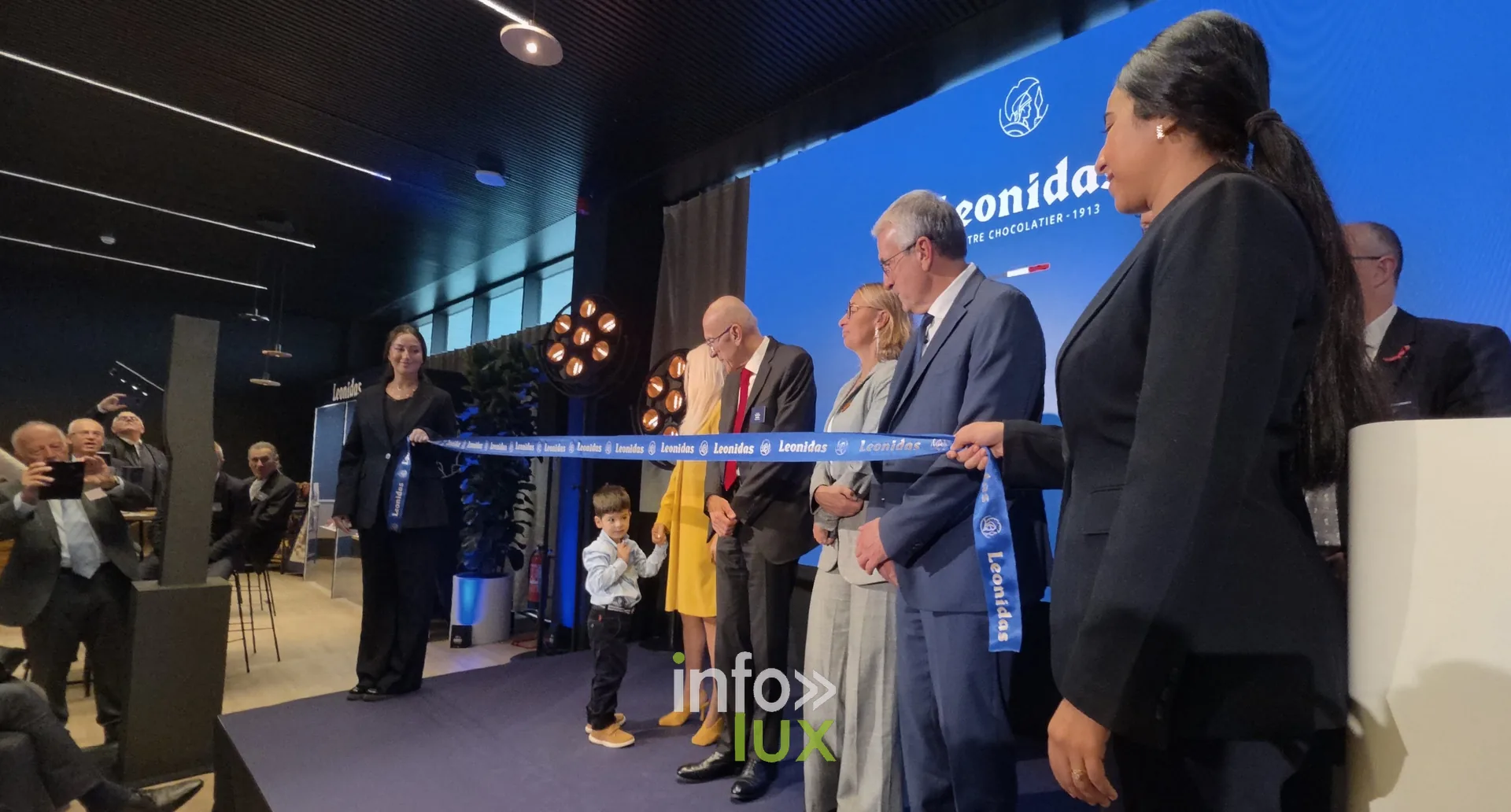 Les officiels devant le ruban inaugural, inauguration du nouveau site Leonidas à Nivelles, 15 octobre 2026 (photo Karolyn Delisé-Hanse) — photo modifiée par ia