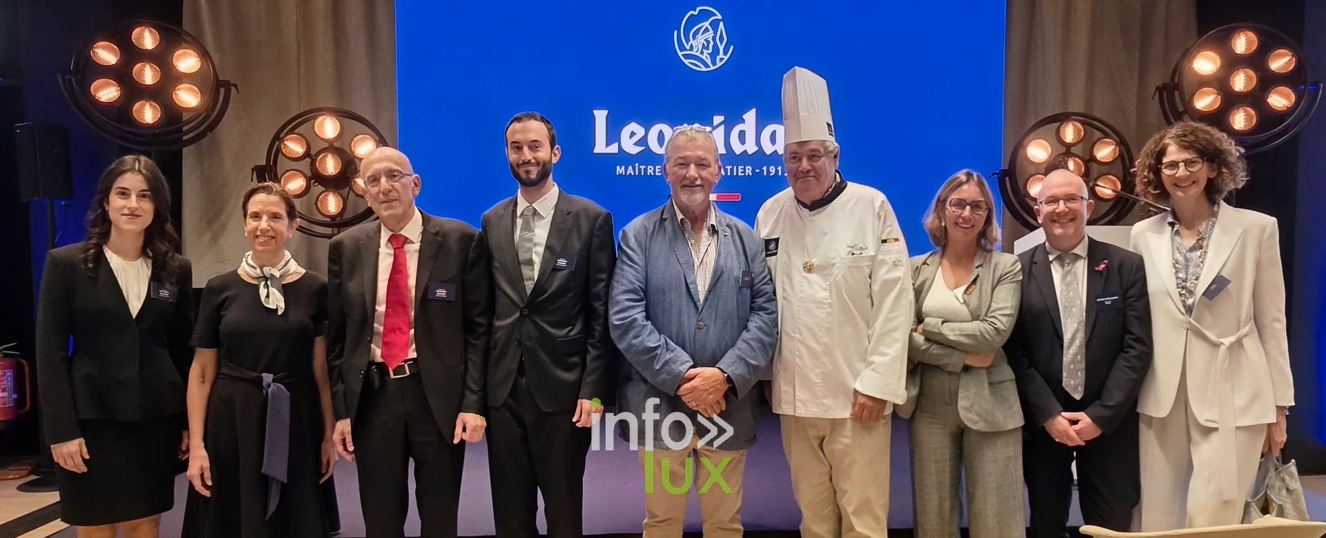 Photo de groupe devant l’écran Leonidas, inauguration du nouveau site Leonidas à Nivelles, 15 octobre 2026 (photo Karolyn Delisé-Hanse) — photo modifiée par ia