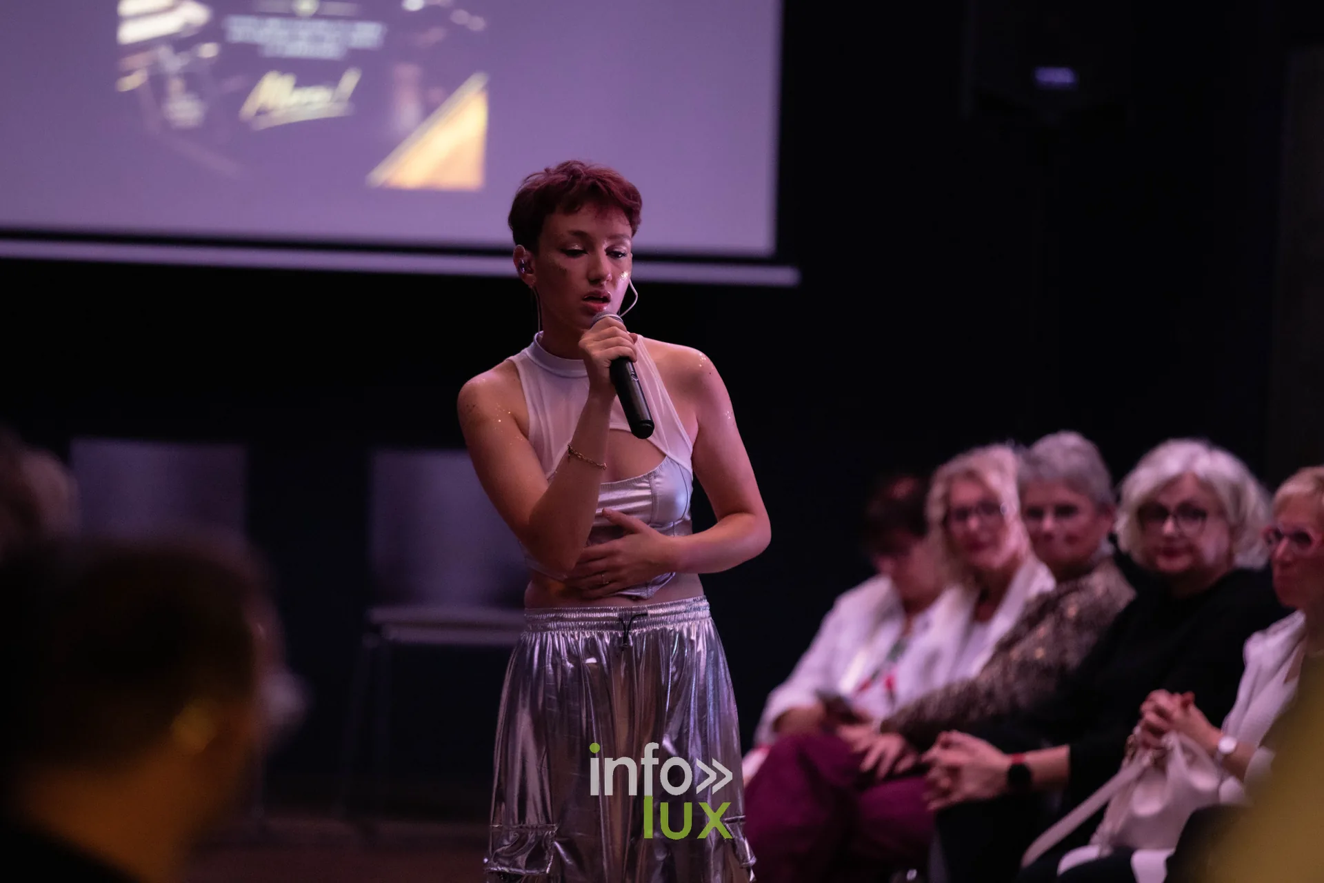 Liège Fashion Week 2026 au Musée Grand Curtius à Liège : chanteuse au micro en tenue argentée dans l’auditorium