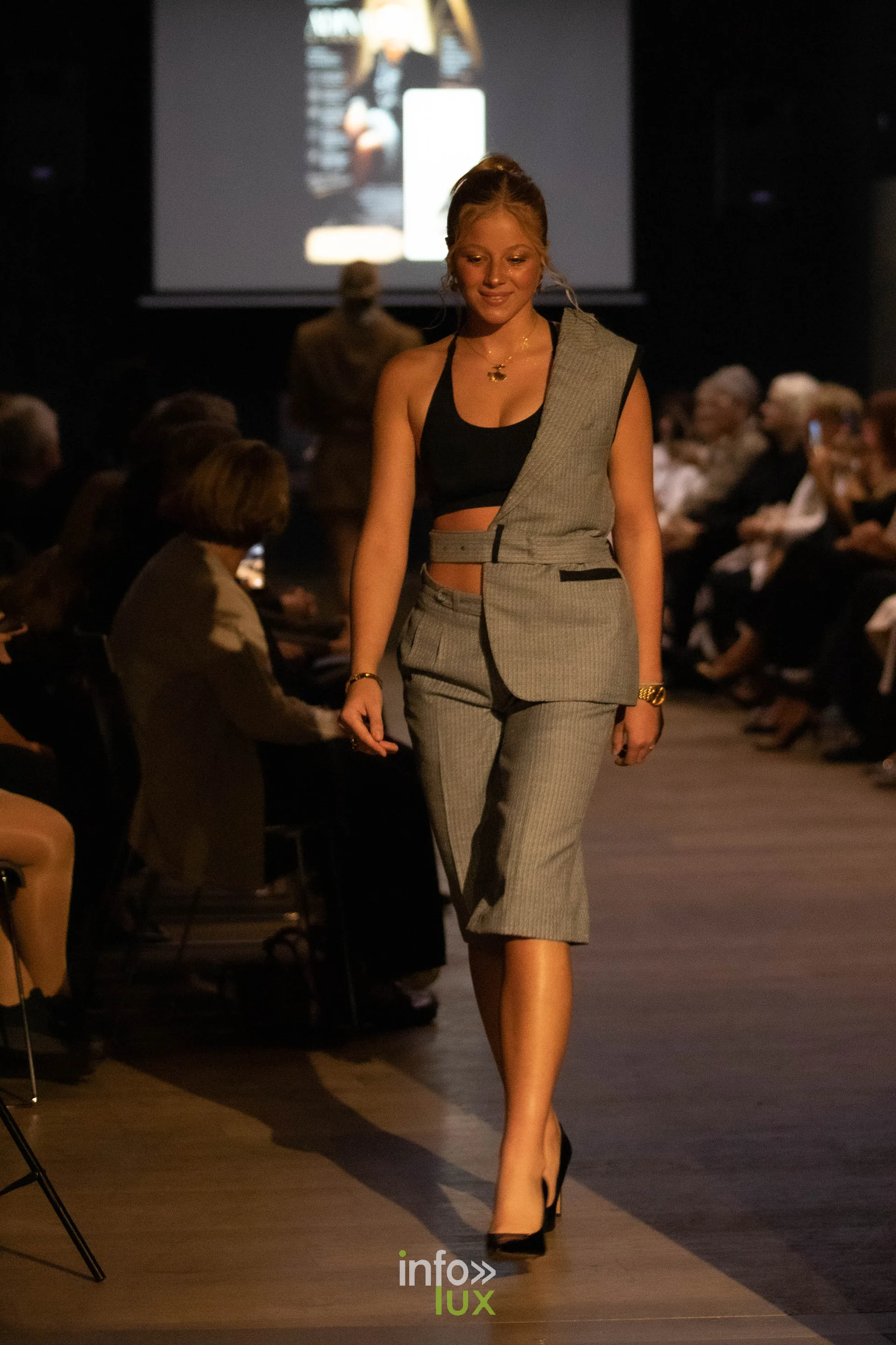 Liège Fashion Week 2026 au Musée Grand Curtius à Liège : mannequin en tailleur gris asymétrique dans l’auditorium