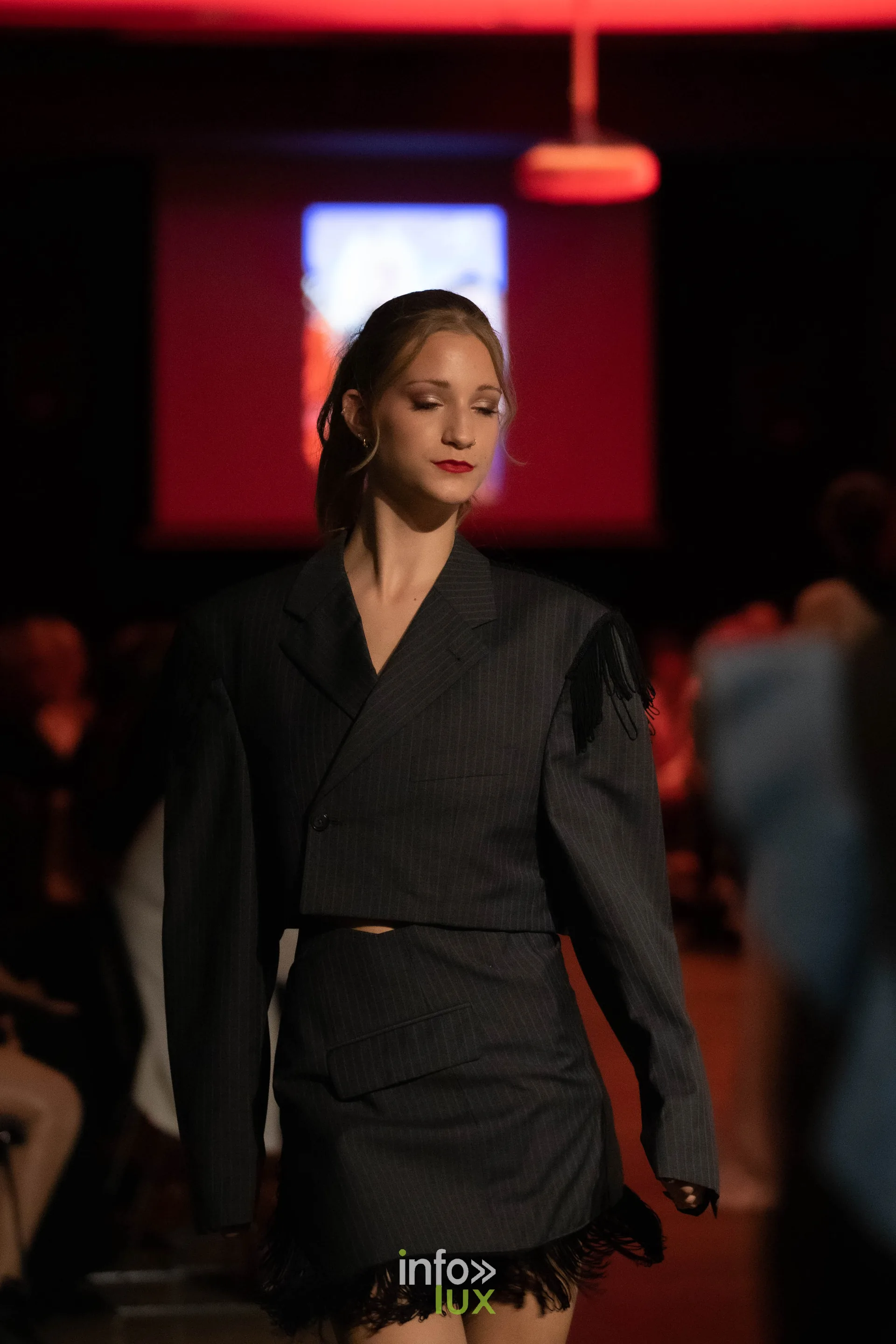 Liège Fashion Week 2026 au Musée Grand Curtius à Liège : mannequin en tailleur gris oversize et jupe bordée de dentelle