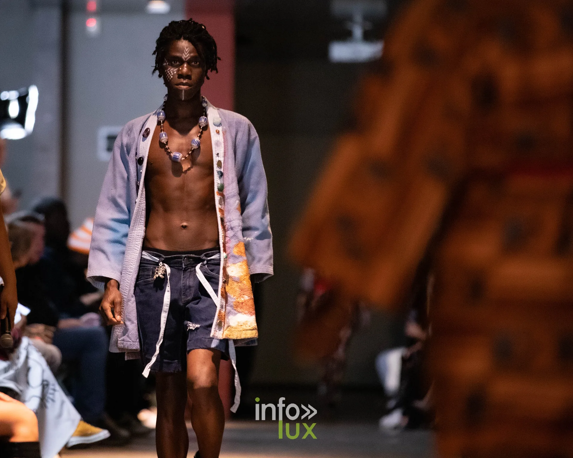 Liège Fashion Week 2026 au Musée Grand Curtius à Liège : mannequin masculin en veste claire à motifs et collier de perles