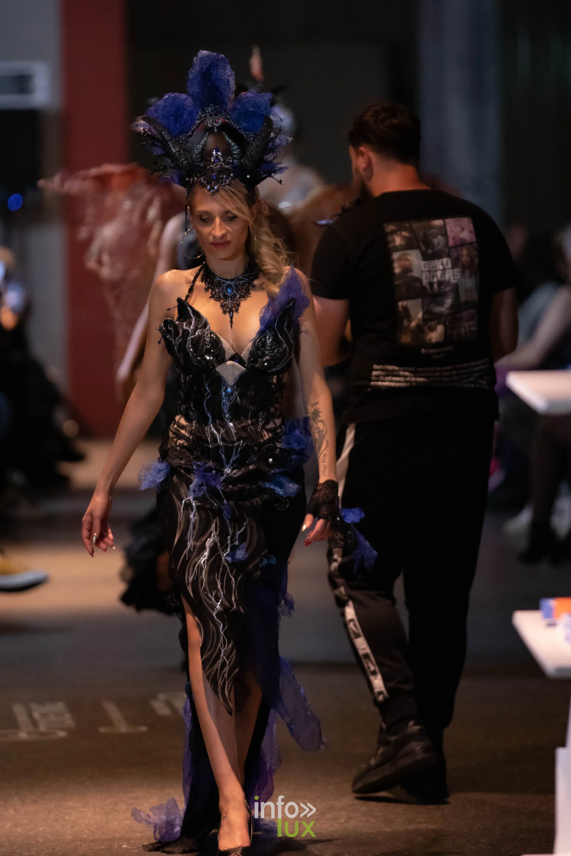 Liège Fashion Week 2026 au Musée Grand Curtius à Liège : mannequin en robe noire à plumes et coiffe bleue