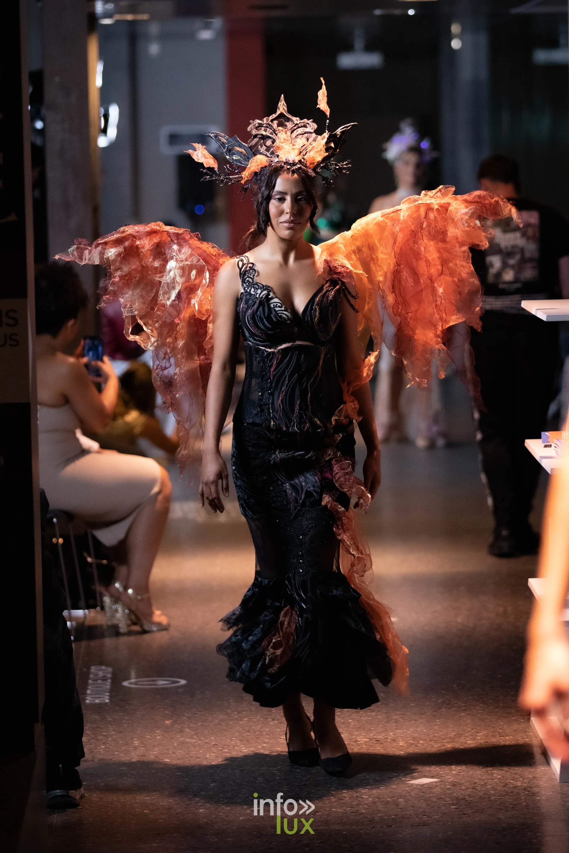 Liège Fashion Week 2026 au Musée Grand Curtius à Liège : mannequin en robe noire à ailes orange et coiffe assortie
