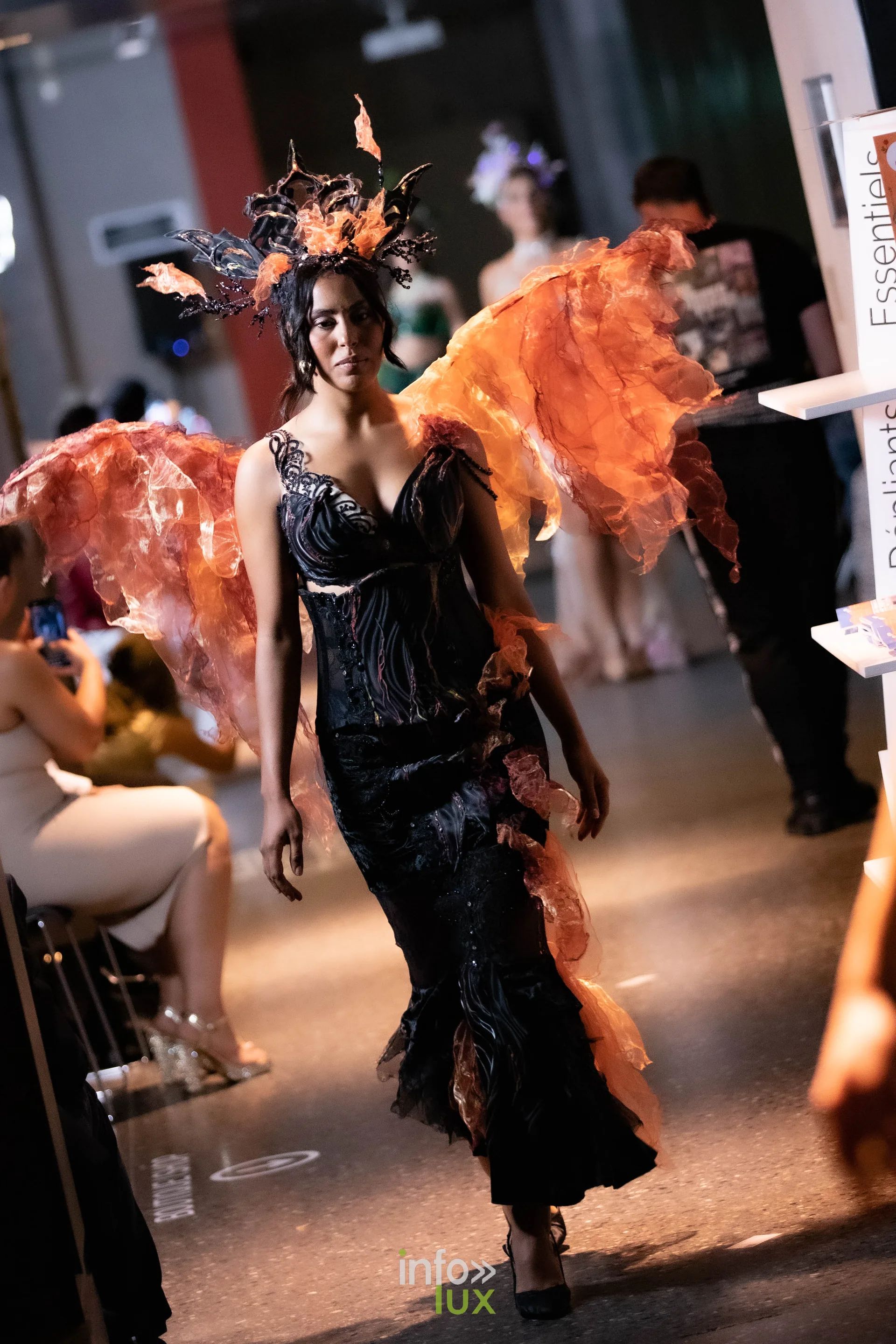 Liège Fashion Week 2026 au Musée Grand Curtius à Liège : mannequin en robe noire à ailes orange sur le podium