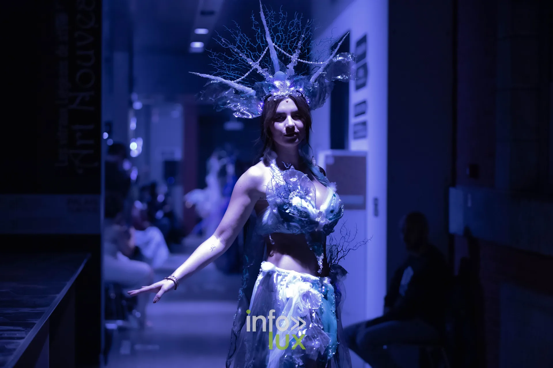 Liège Fashion Week 2026 au Musée Grand Curtius à Liège : mannequin en tenue bleue lumineuse et coiffe de branchages sous lumière bleue