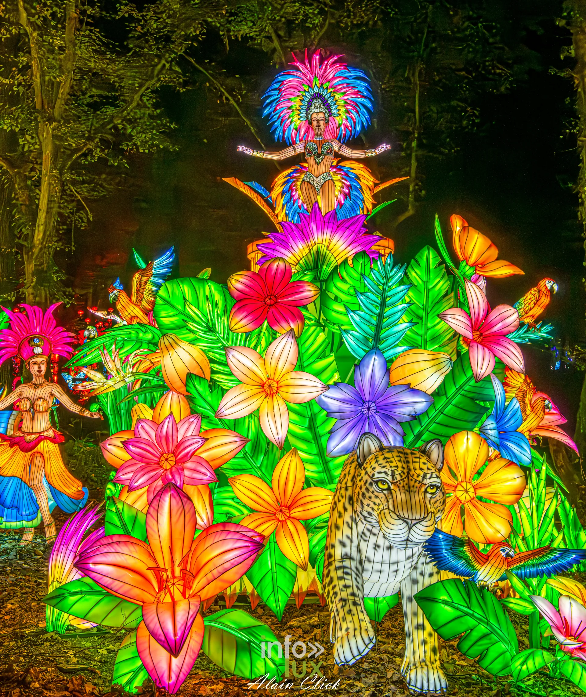 Luminescences 2026-2027 au Zoo d’Amnéville : danseuse coiffée de plumes et félin parmi des fleurs tropicales (photo Alain Click)