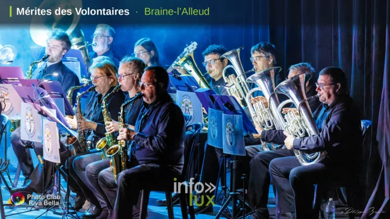 Des musiciens de l’Harmonie Royale de Mont-Saint-Pont sur la scène du POP à Braine-l’Alleud, avec le bandeau « Mérites des Volontaires · Braine-l’Alleud »
