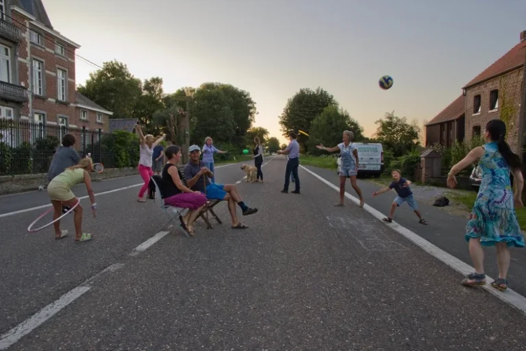 Des habitants jouent ensemble dans une rue de village en fin de journée