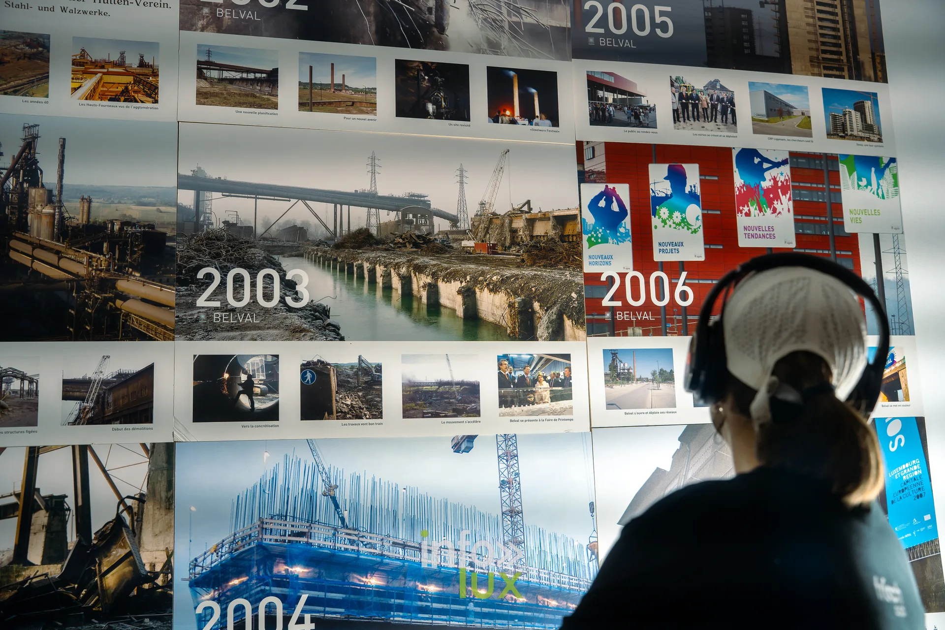 Nuit de la Culture 2026 à Esch-Belval : une visiteuse avec un casque audio devant des photos de la transformation de Belval, de 2003 à 2006