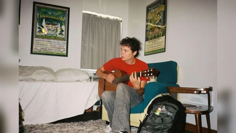 Le chanteur américain Oscar Lindsey assis dans un fauteuil, guitare classique en main