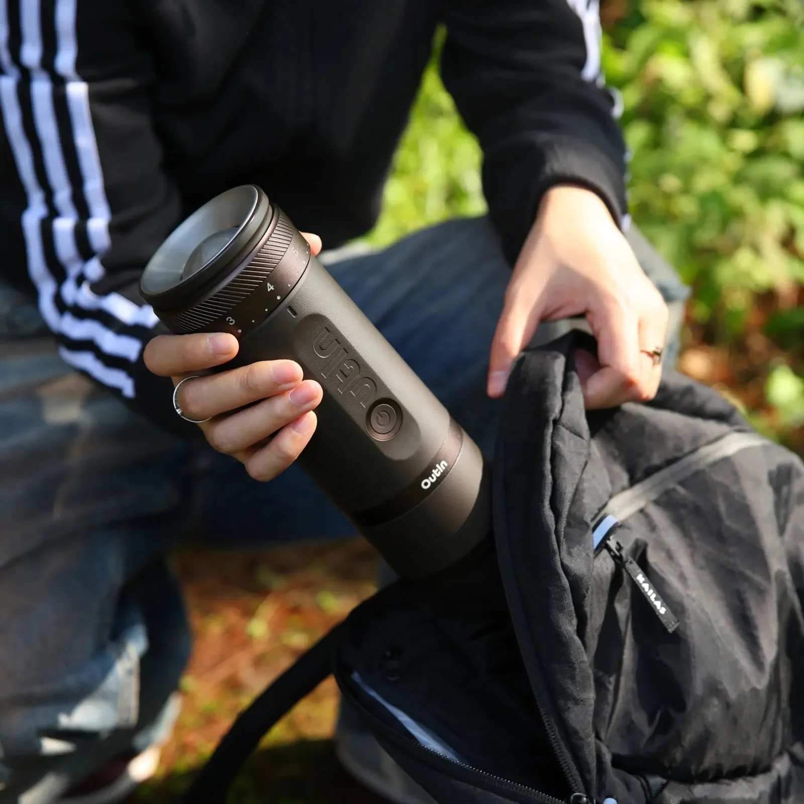 Moulin à café électrique portable OutIn Fino tenu en main en extérieur