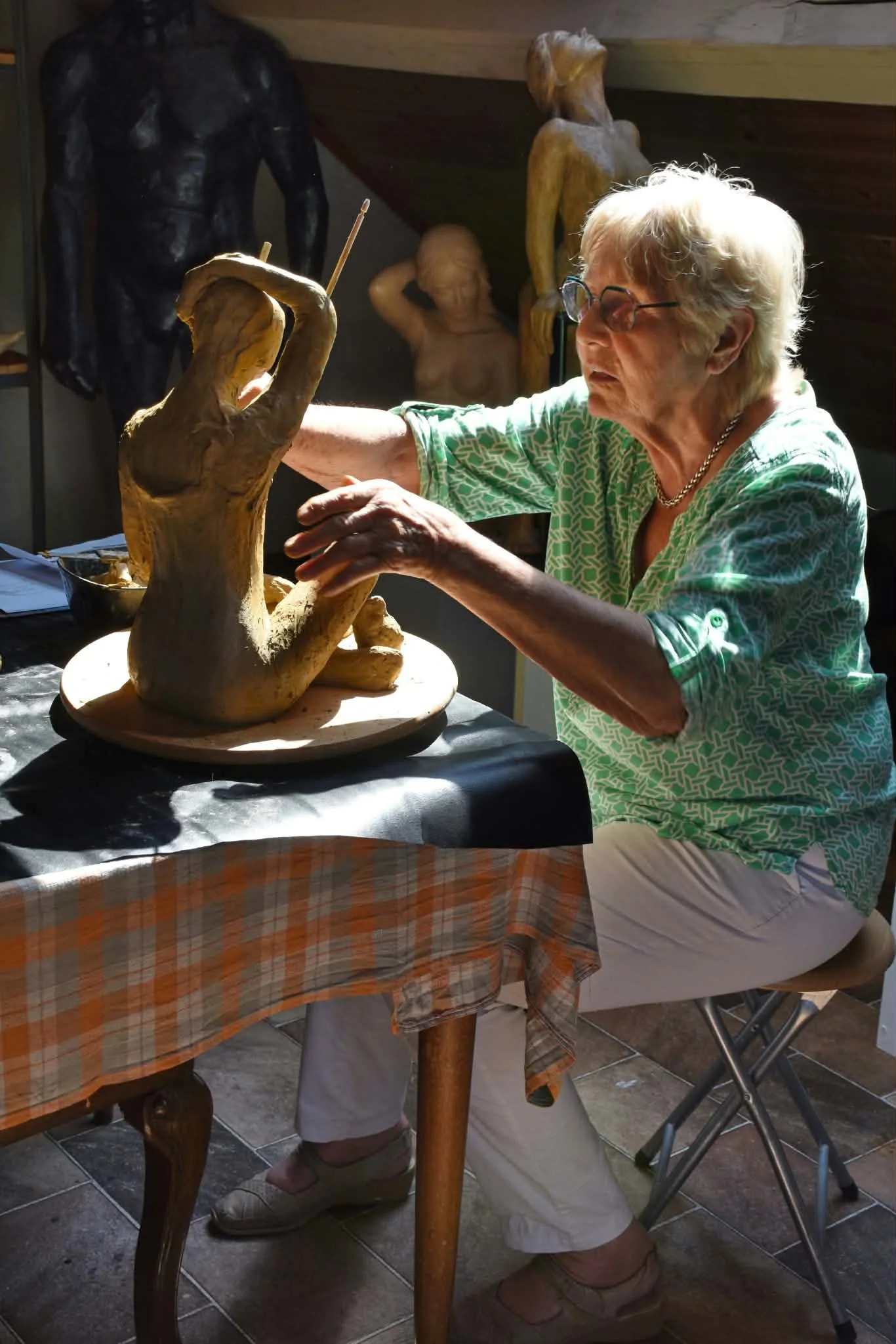 Ursula Förster façonnant une figure en terre sur sa table de travail