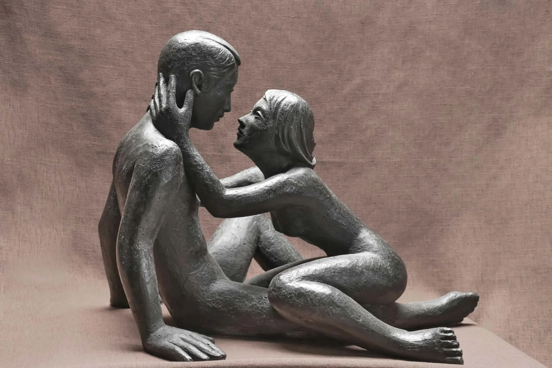 Sculpture d’un couple assis, l’homme tenant le visage de la femme