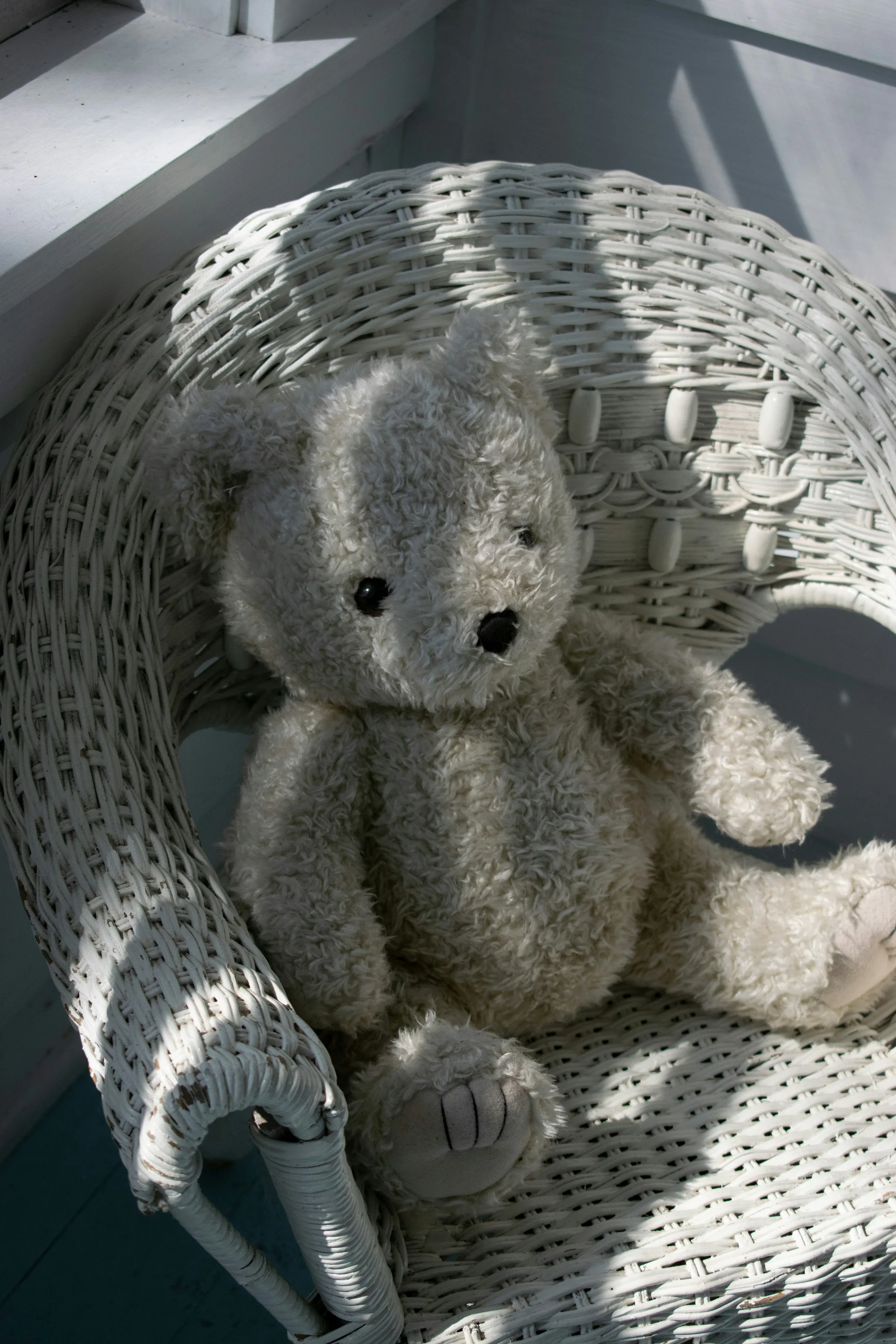 Un ours en peluche assis dans un fauteuil en osier