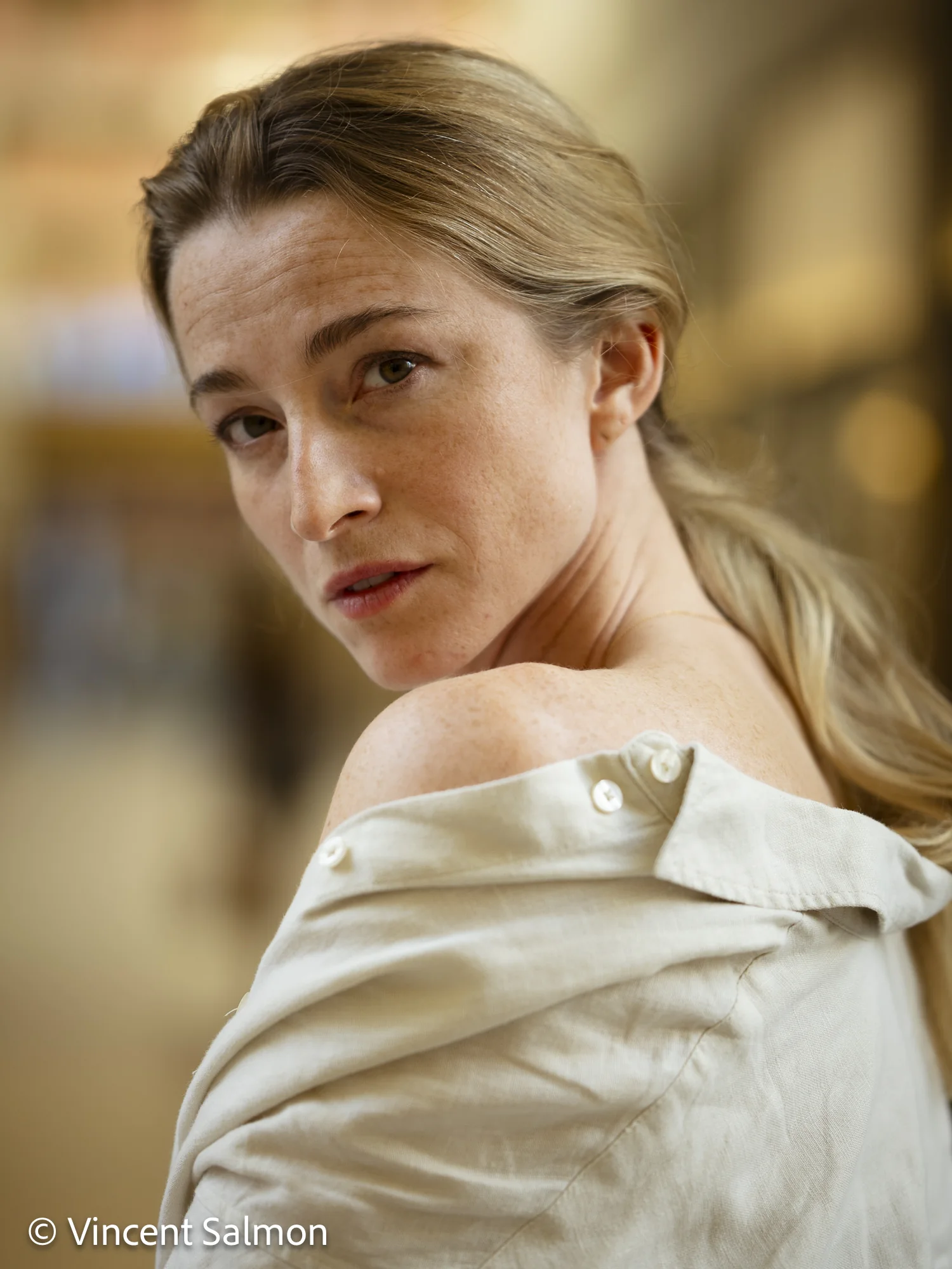 Photo de Vincent Salmon : portrait couleur d’une femme au regard par-dessus l’épaule
