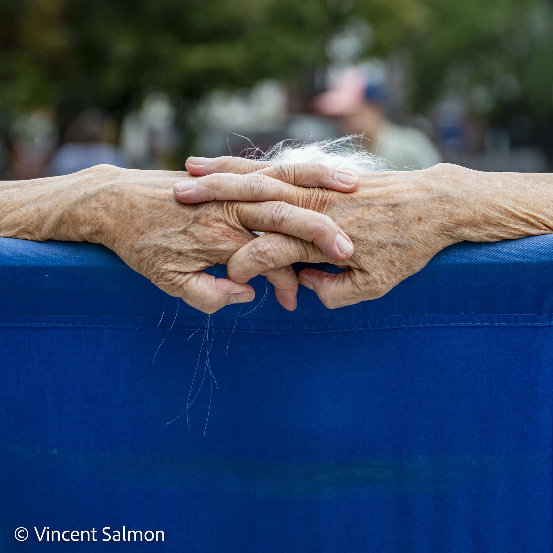 Photo de Vincent Salmon : des mains croisées posées sur une barrière bleue