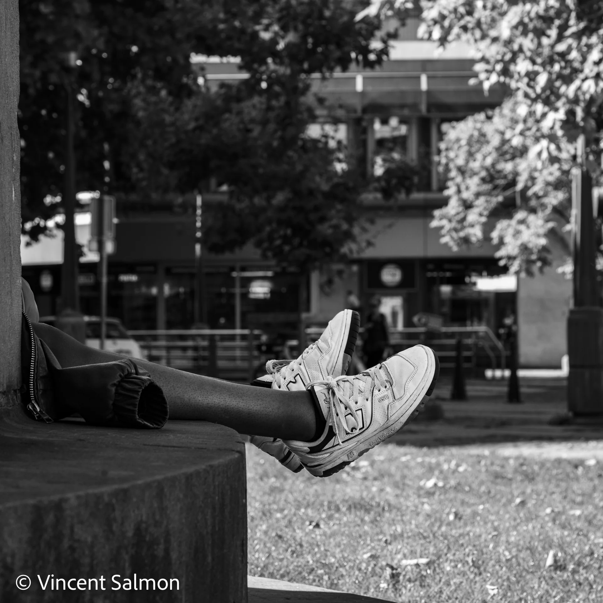 Photo de Vincent Salmon : des pieds en baskets posés sur un muret