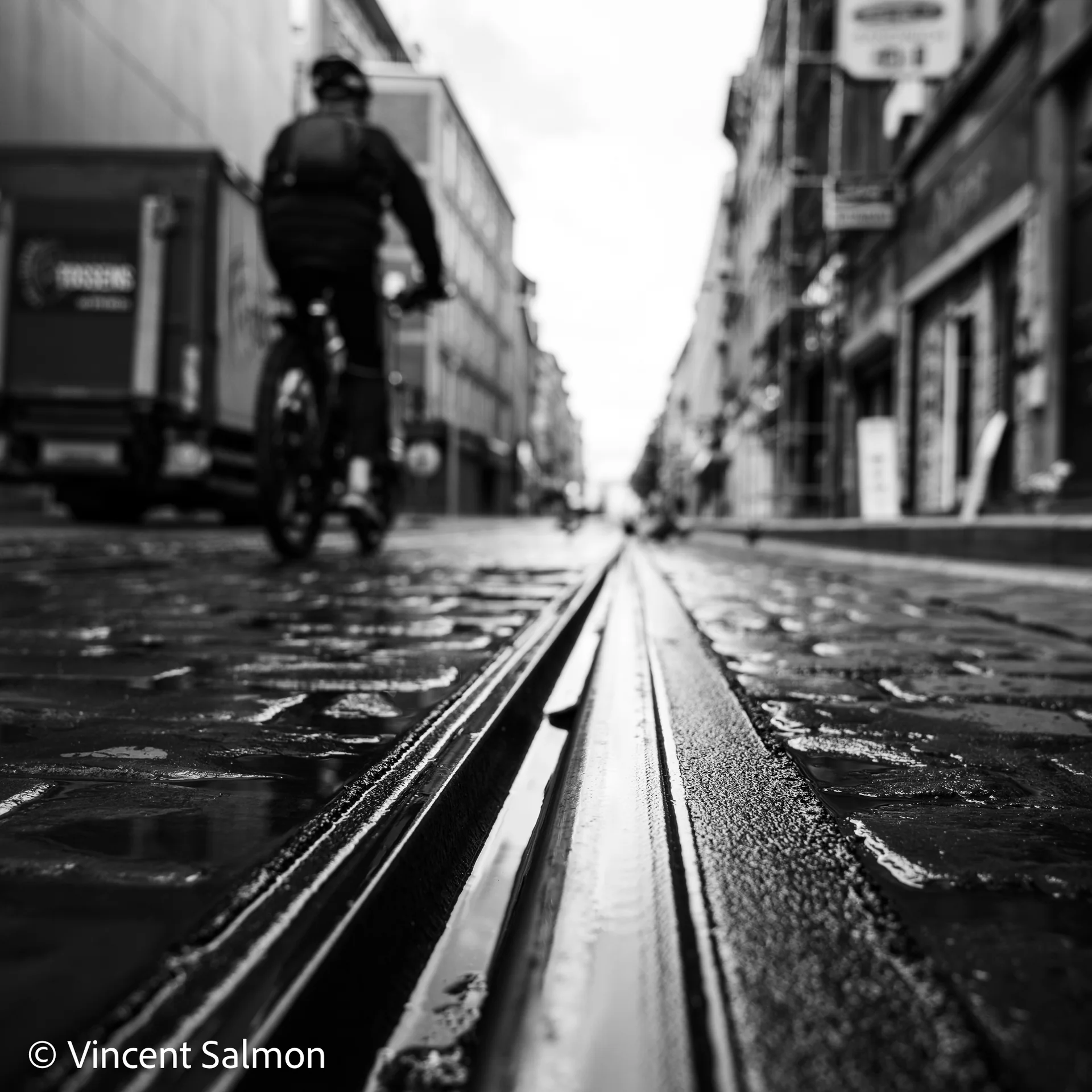 Photo de Vincent Salmon : un cycliste sur les pavés mouillés, au ras des rails