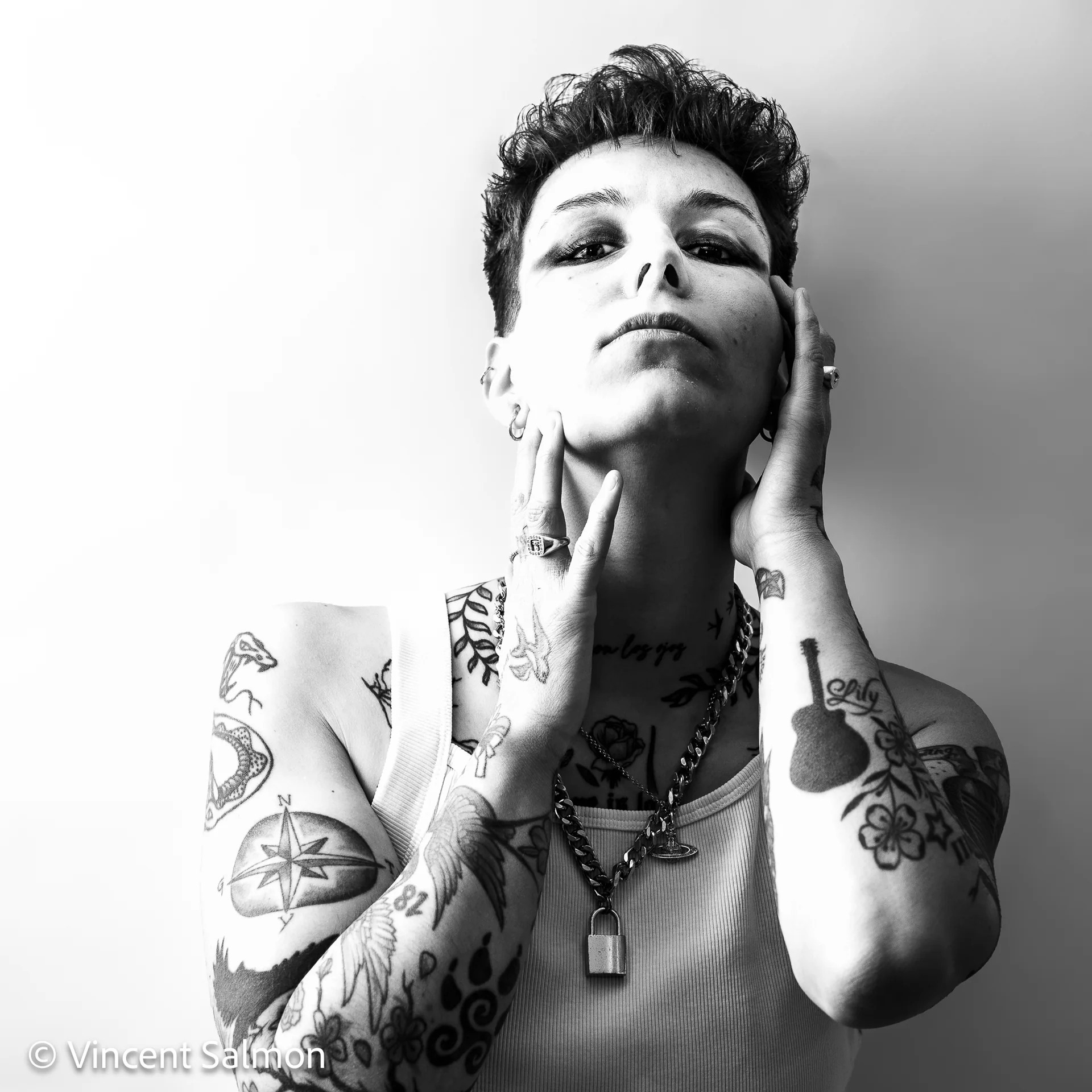 Photo de Vincent Salmon : portrait d’une personne tatouée, les mains sur le visage