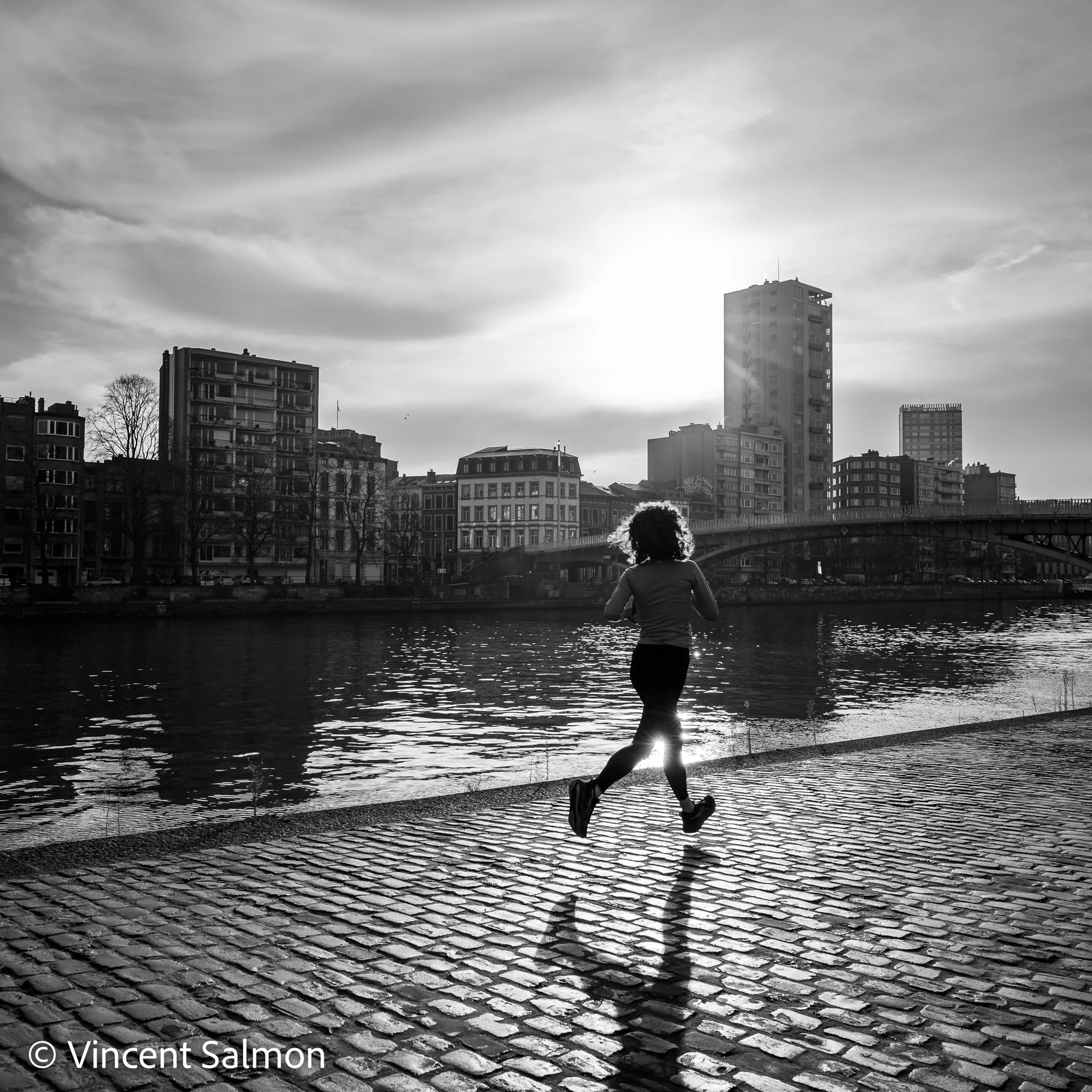 Photo de Vincent Salmon : une joggeuse sur les pavés d’un quai, à contre-jour