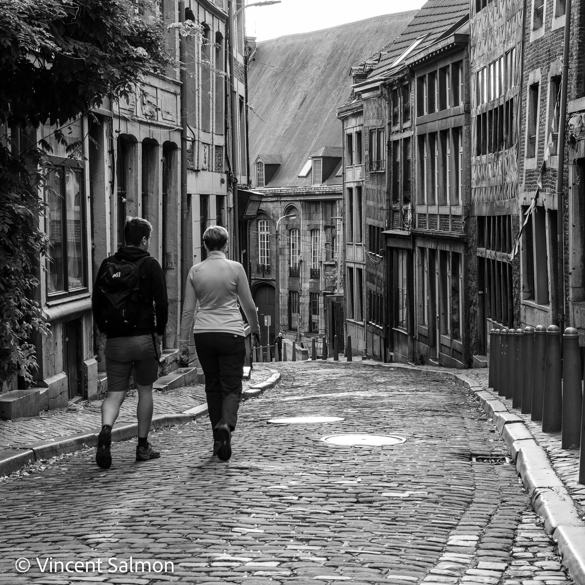 Photo de Vincent Salmon : deux passants dans une rue pavée en pente