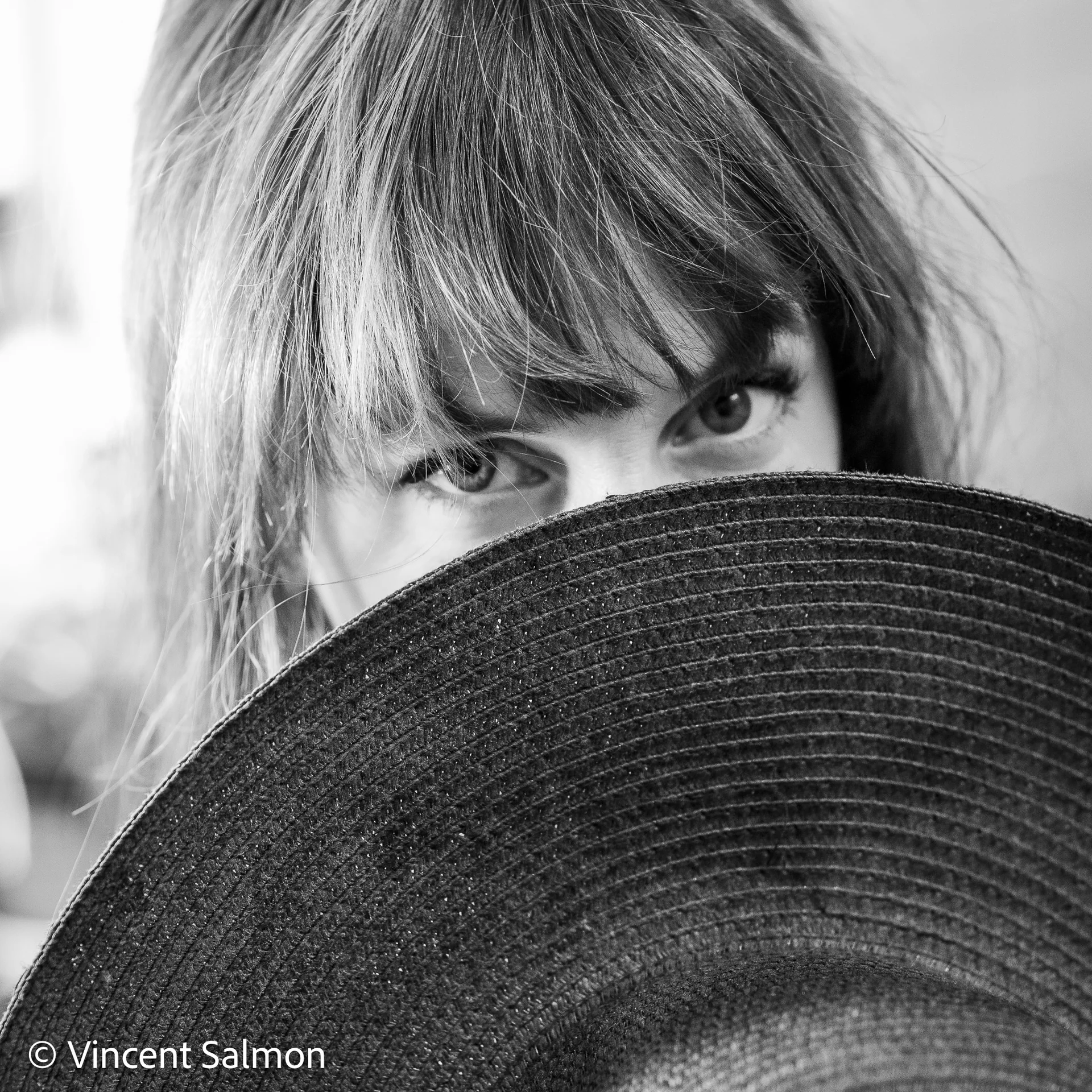 Photo de Vincent Salmon : une femme cache le bas de son visage derrière un chapeau